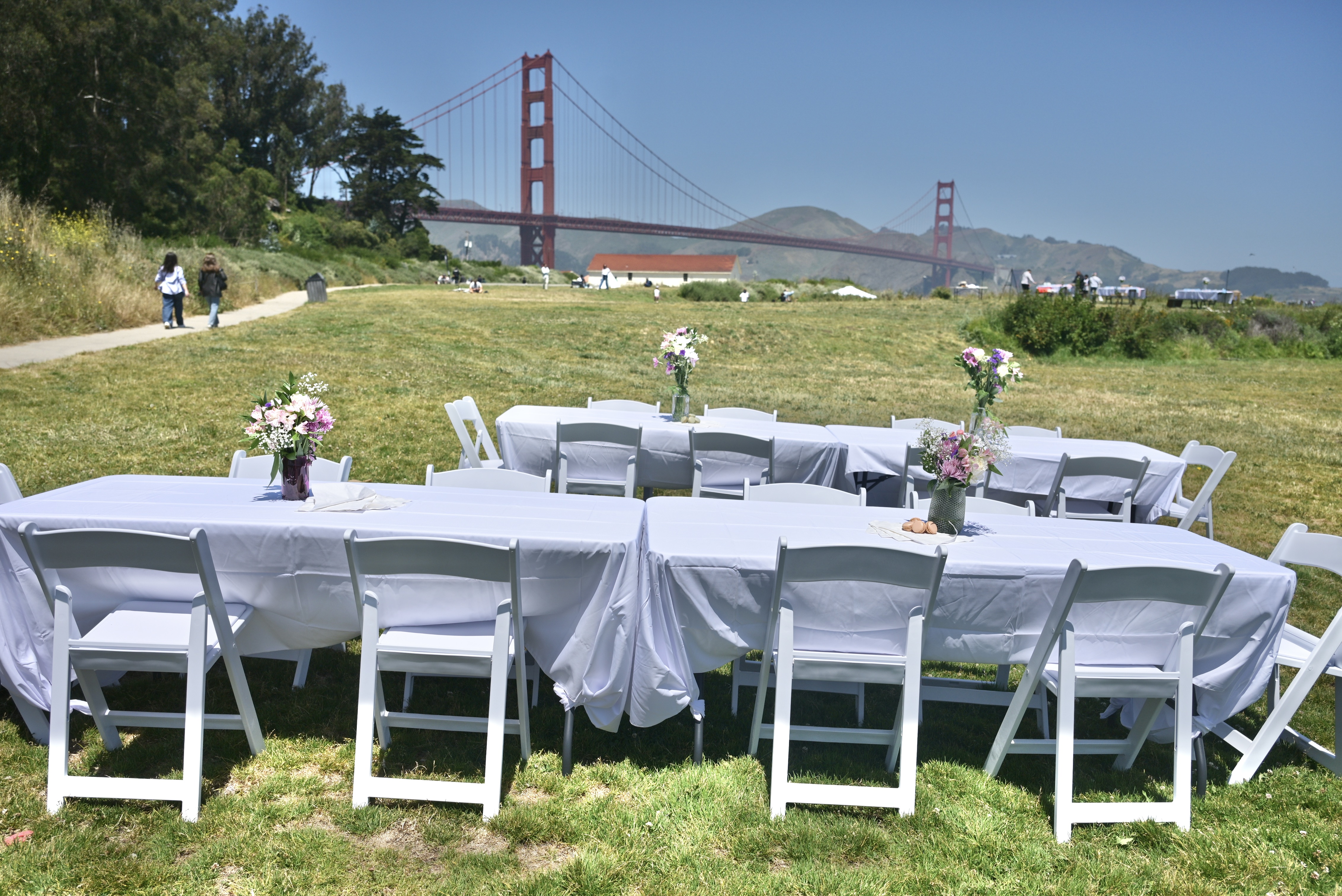 Tables and chairs set up on the grass with the Golden Gate Bridge in the background