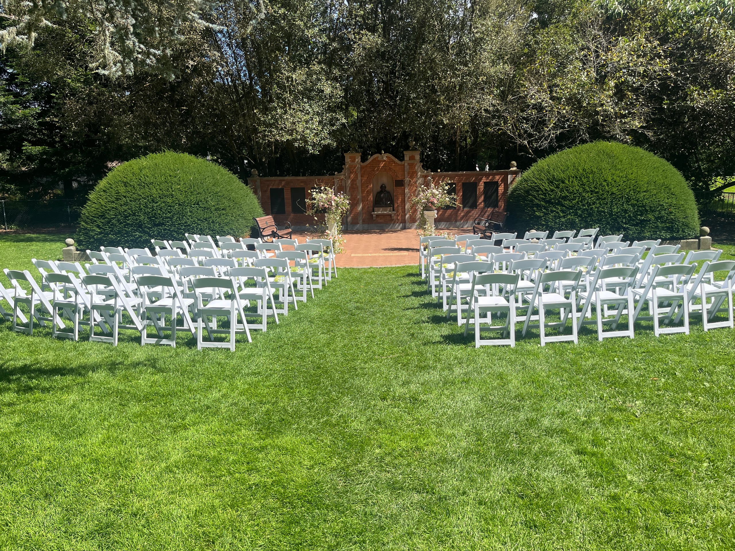 Rows of white folding chairs set up on the lawn for a wedding ceremony in the Shakespeare Garden in San Francisco